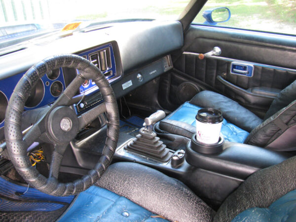 A 1973-1981 Camaro and 1970-1981 Firebird Armrest and Drink Holder in a Camaro